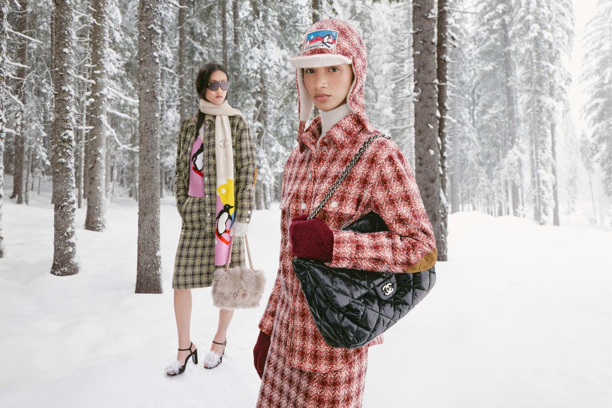 Две модели в клетчатых пальто среди заснеженных елей — кадр кампании Chanel Coco Neige 2026