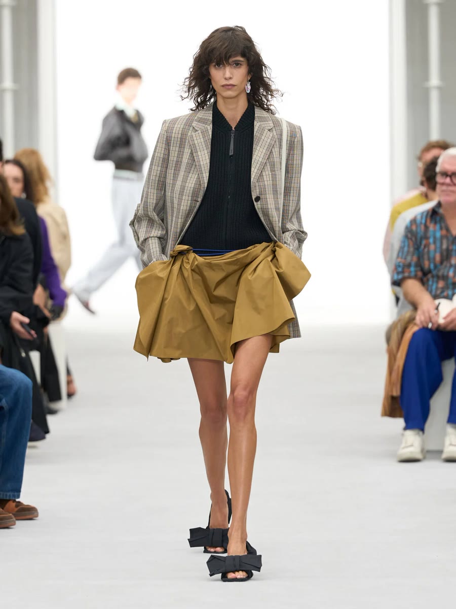 Loewe весна-лето 2027, образ 2: клетчатый пиджак и юбка цвета хаки с драпировкой