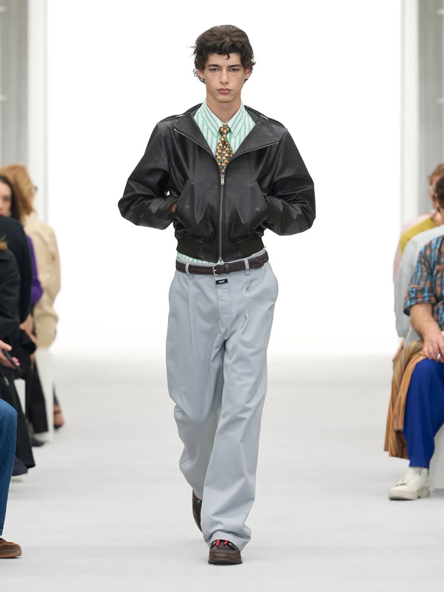 Loewe весна-лето 2027, образ 3: чёрная кожаная куртка, рубашка в полоску, галстук и серые брюки