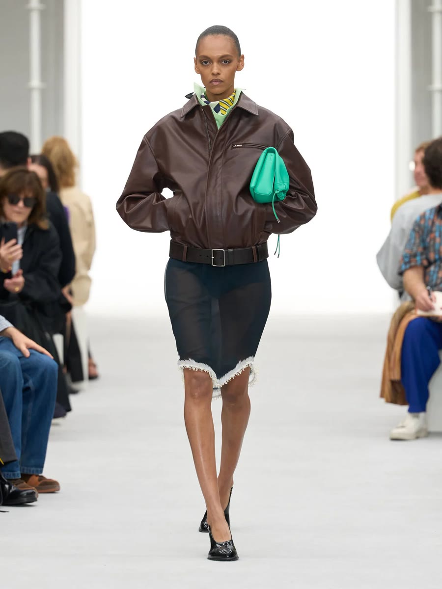Loewe весна-лето 2027, образ 9: коричневая кожаная куртка и тёмная юбка с бахромой