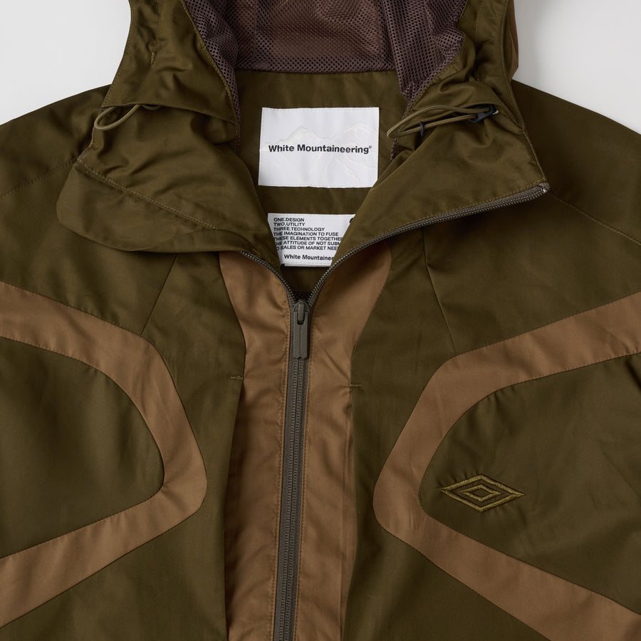 Куртка цвета хаки White Mountaineering × Umbro: изогнутые вставки цвета терракоты и логотип Umbro на груди